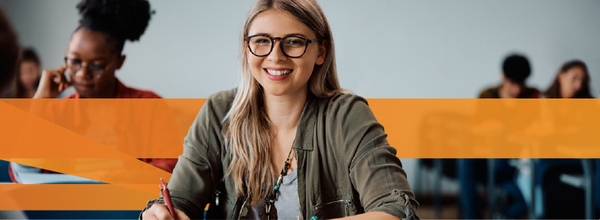 Higher education student at a desk with pen in hand.
