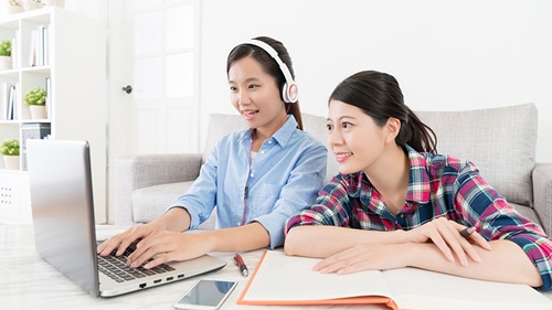 Two learners engaged with a laptop
